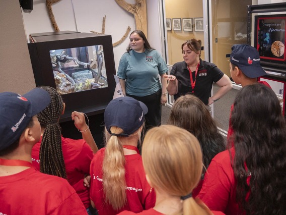 Two young women talk to a bunch of kids during a tour of the Arizona Poison and Drug Information Center.