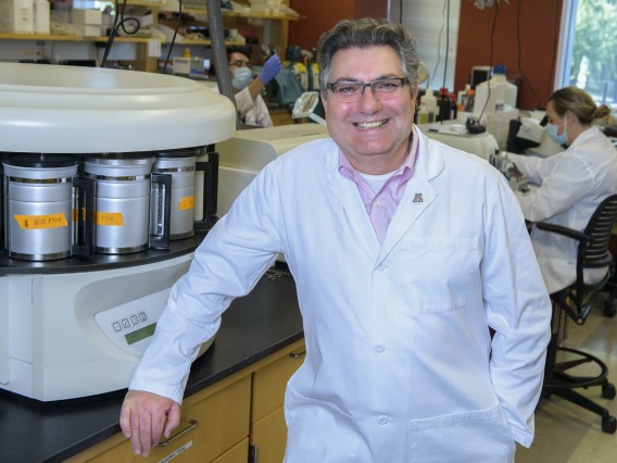 Researcher Klearchos Papas, PhD, poses in a lab dressed in a white lab coat.