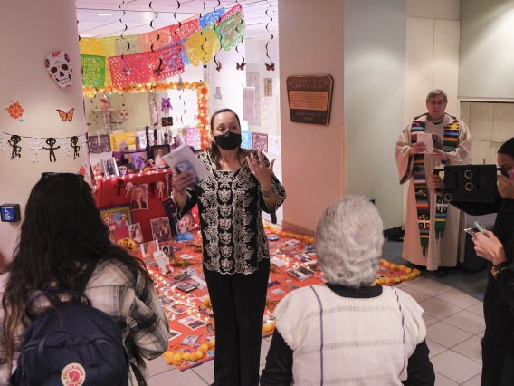 Lydia Kennedy (center), senior director of the UArizona Health Sciences Office of Equity, Diversity and Inclusion, speaks to about 75 attendees at the annual Dia de Los Muertos blessing ceremony in the Health Sciences Library. The altar behind her is filled with photos and remembrences from Health Sciences faculty, staff and students.