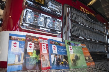 Six Advanced Hazmat Life Support manuals displayed leaning against a fire truck.