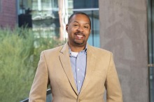 Photo of Michael D.L. Johnson in a blue shirt with a tan sports coat. 
