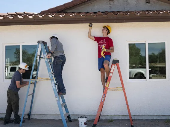 (From left) Volunteers Sawyer Thein, MD, Esteban Valle, MD, and Kevin Brandecker, MD, all first-year emergency medicine residents at Banner – University Medical Center Tucson, paint the eaves and trim on a Habitat for Humanity Tucson house during the EM Day of Service in late September.