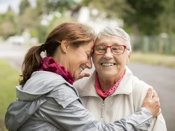 Happy senior woman and caregiver walking outdoors