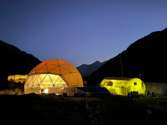 Domed camping tents glow at night.