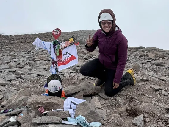 Nicola Baker crouches next to a memorial at the summit of Aconcagua, the tallest mountain in the Americas.