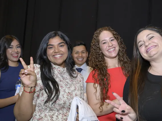 Five University of Arizona R. Ken Coit College of Pharmacy students smile as a couple of them flash peace signs.