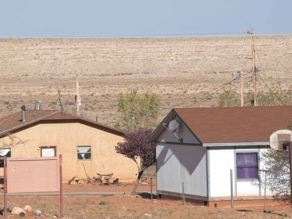 A pair of houses, one white and one tan, on the Navajo Nation in Arizona.