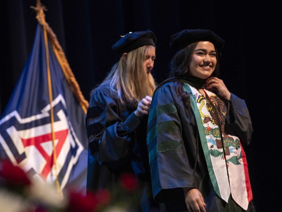 Medical student Jovanna Figueroa is hooded by University of Arizona College of Medicine – Phoenix professor Kathleen Brite Hillis during the graduation ceremony. Both are wearing graduation regalia. 