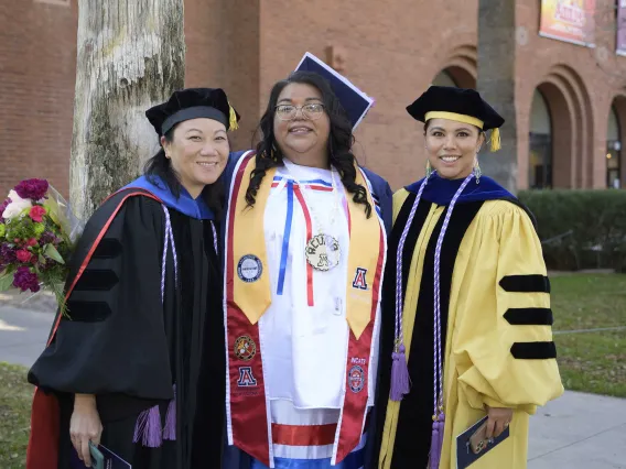 Two U of A College of Nursing faculty members pose with a graduating student after the college’s convocation ceremony.