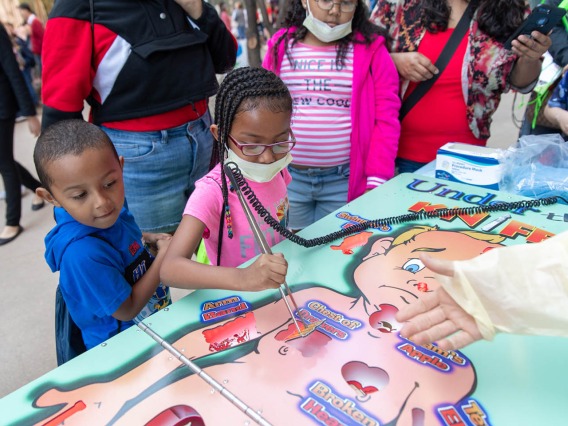 Children practice medical skills on life-sized Operation game sponsored by Phoenix Children's Hospital.