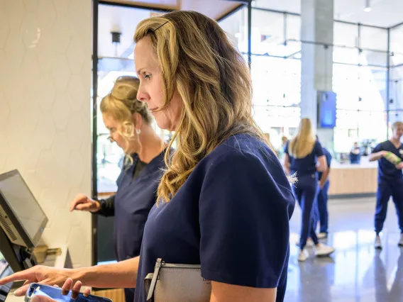 Two women use the computer screen at a kiosk to order food in the cafe. 