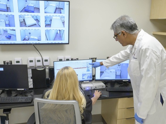 Sairam Parthasarathy, MD, director of the University of Arizona Health Sciences Center for Sleep, Circadian and Neuroscience Research, reviews test data in the control room of the center’s new facility with lead sleep technologist Sicily La Rue. 