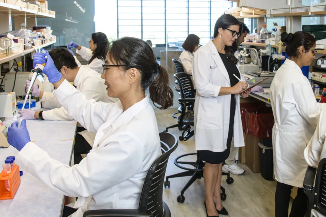 Female professor evaluating students in lab.