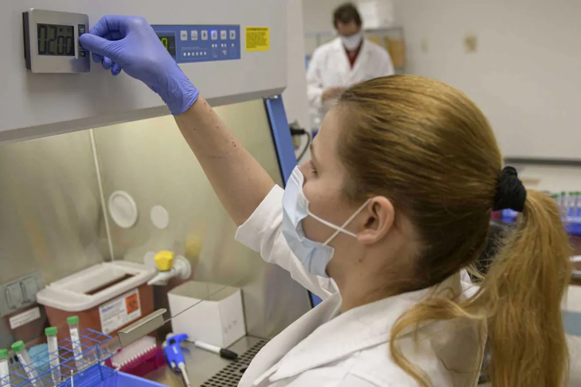 Female researcher tending to machine