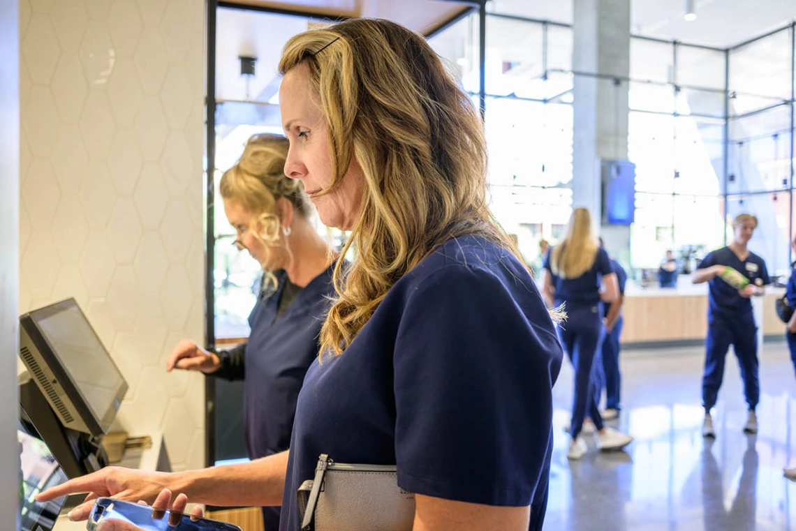 Two women use the computer screen at a kiosk to order food in the cafe. 