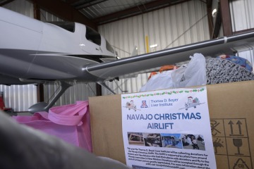 Christmas donations in a box waiting in an airplane hanger to be loaded onto the waiting plane