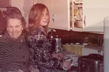 old photo of a grandmother and her granddaughter in a kitchen