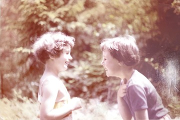 Profile photos of two young girls facing each other and laughing in a forest.
