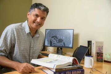 portrait of immunologist Deepta Bhattacharya at his desk at the University of Arizona Health Sciences