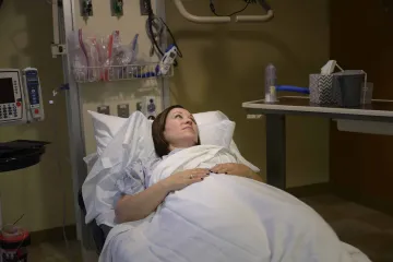 Woman in hospital bed under bright lights