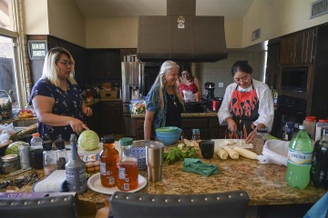 Diné College students Angel Leslie (left), Alyssa Joe (back) and program manager Kaitlyn Haskie (right) make fry bread and prepare mutton stew for a dinner at the home of Kathleen E. Rodgers, PhD.
