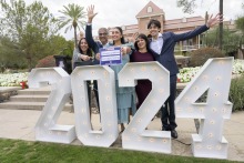 a medical student and her family celebrate behind a large 2024 sign 